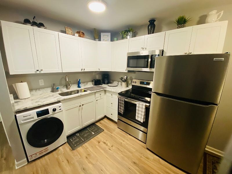 Combo washer/dryer, toaster, coffee maker, electric stove, microwave and refrigerator with quartzite countertops and stainless steel appliances