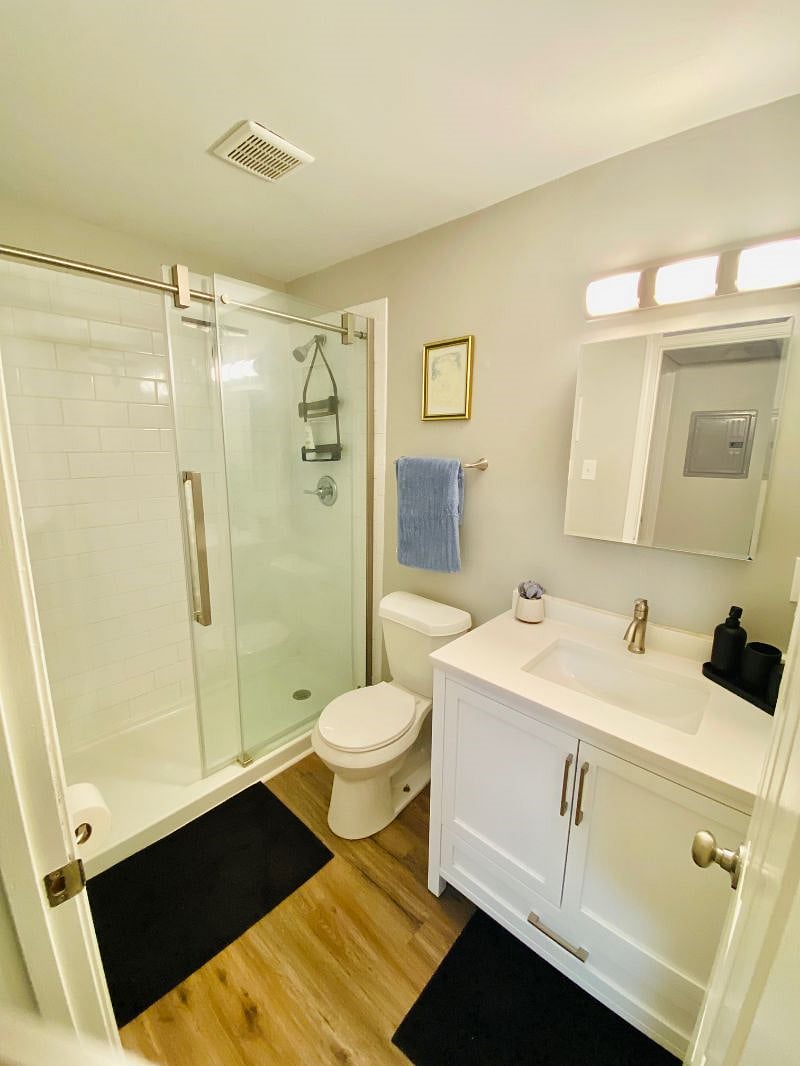 Glass shower door with subway tiled finishes, new vanity and mirror