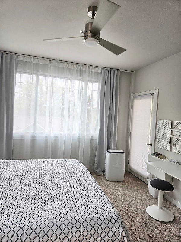 Primary bedroom with portable A/C, ceiling fan, and private balcony access