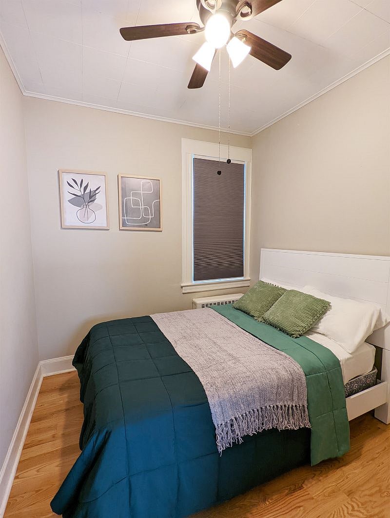 Cozy 2nd bedroom with blackout shades, ceiling fan, and closet with storage