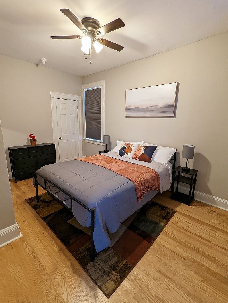 Comfortable main bedroom w/ dresser, full size floor mirror, blackout shades, side tables w/ built-in USB, ceiling fan, and large closet with storage space