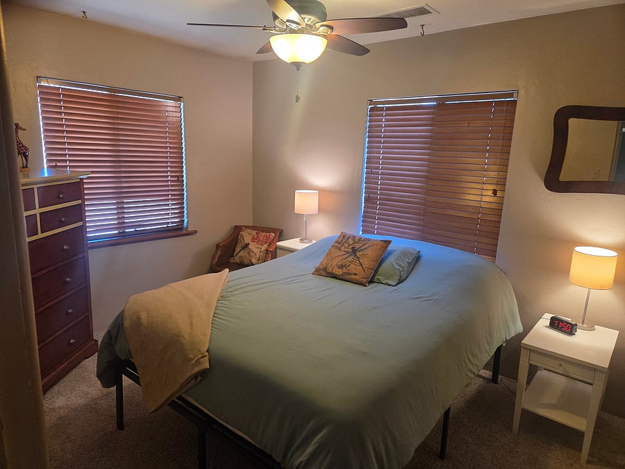 Guest bedroom with Queen mattress, 2 nightstands, tall dresser and chair.