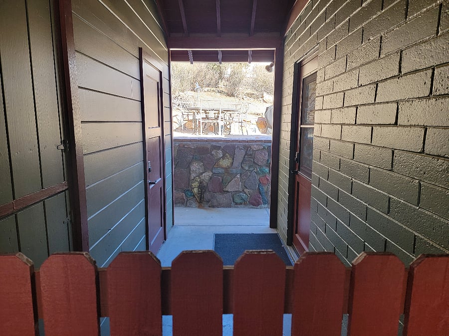 Looking through breezeway to patio. Back door on right, storage shed on left.