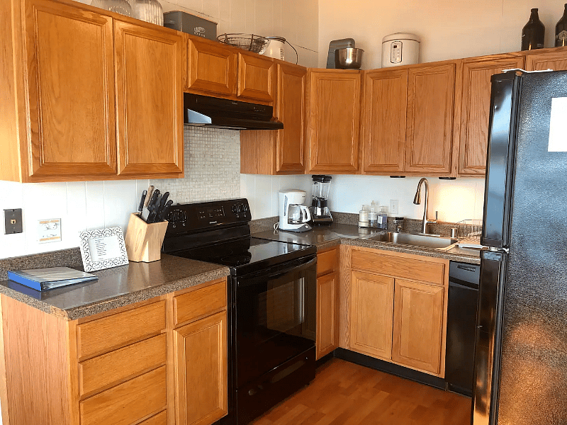 Kitchen with natural wood cabinets, oven and cooktop and microwave. Sink also provides on deman hotwater.