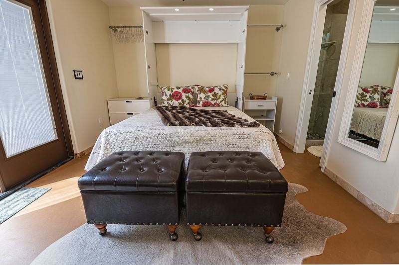 Two storage ottomans at foot of the queen bed. One three drawer dresser to left of the bed. One rolling storage cart to right of the bed. Closet rails to hang clothes on each side of bed. Full size mirror on wall.
