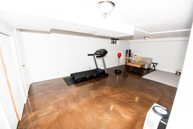 Weights, treadmill, and yoga gear in the main basement space, as well as free standing punching bag