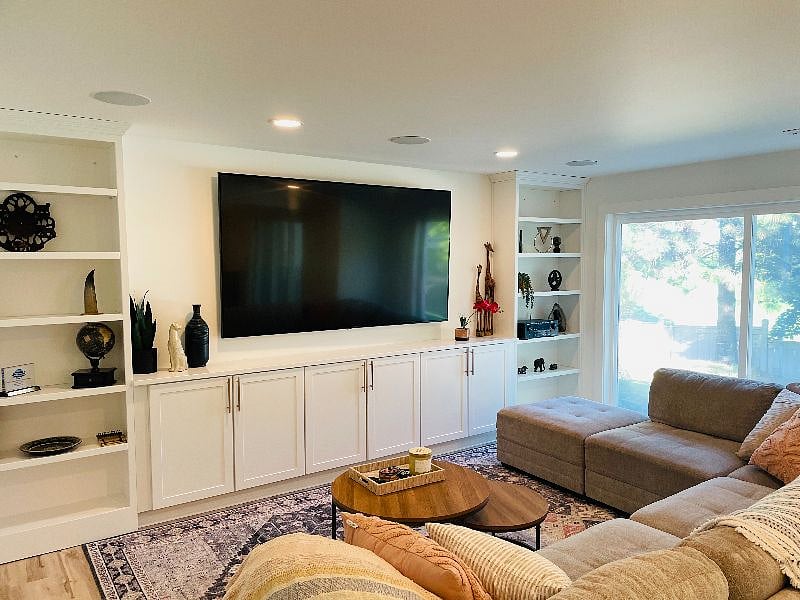 Living room located in the basement. 96" TV and large couches with modern coffee table