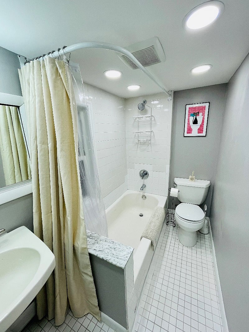 Tiled bathroom with insulated bathtub and ample storage shelves. 