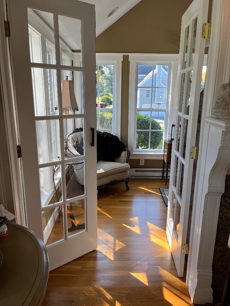 Sunroom for reading with French doors and electric fireplace heating unit.