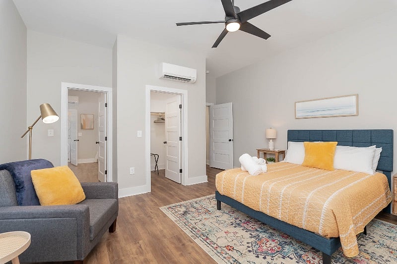 Large bedroom with queen-sized bed and nightstands, walk-in closet, TV, dresser and en-suite full bathroom.