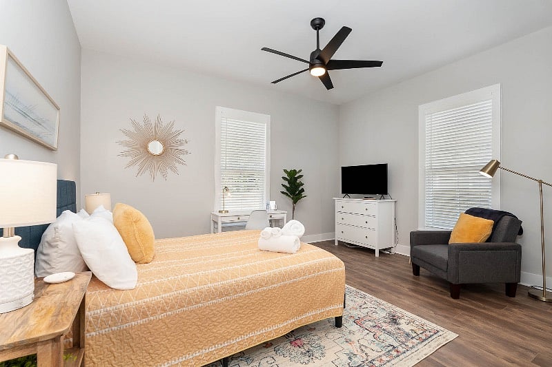 Large bedroom with queen-sized bed, nightstands, TV, dresser and dedicated work space.