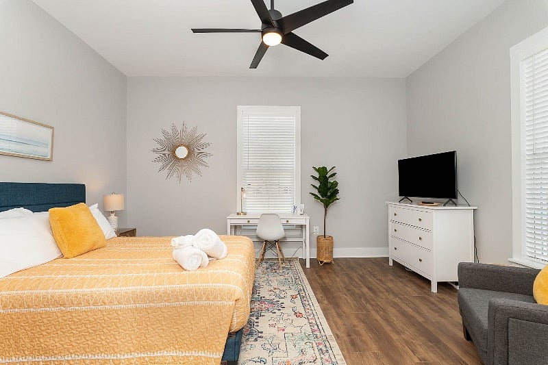 Large bedroom with queen-sized bed, nightstands, TV, dresser and dedicated work space.