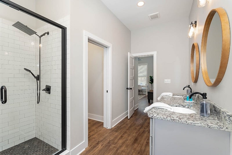 Large full bathroom with tiled walk-in shower, dual sink vanity, and washer and dryer closet. The bathroom is accessible directly from the bedroom or from the hallway for guests.