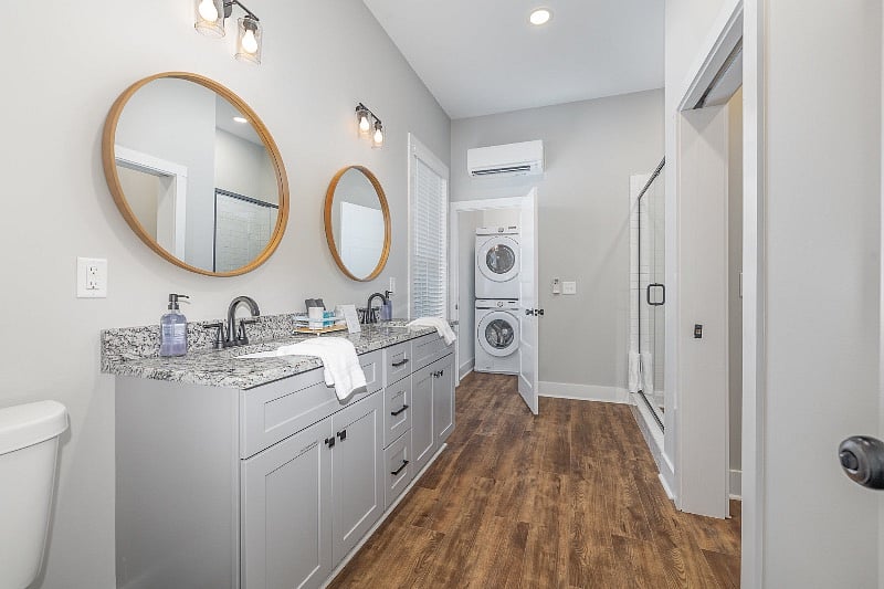 Large en-suite bathroom features dual-sink vanity, tiled walk-in shower and full-sized washer and dryer.