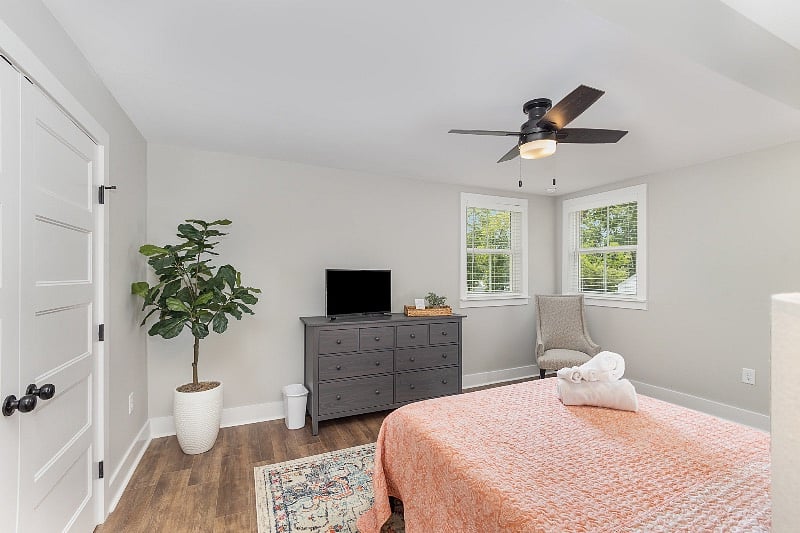 Large bedroom with queen-sized mattress, ceiling fan, large closet, dresser and TV.