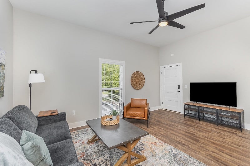 Spacious and open-concept living room with comfortable seating, 55" TV and ceiling fan.