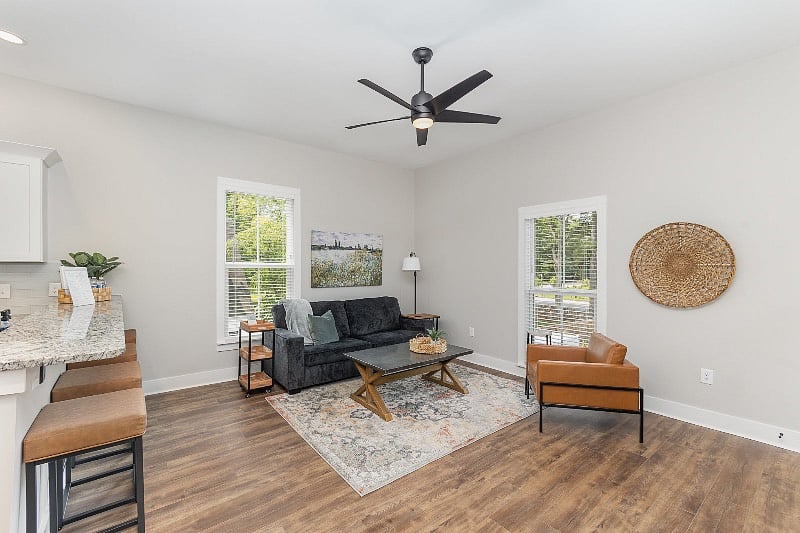 Spacious and open-concept living room with comfortable seating, 55" TV and ceiling fan.