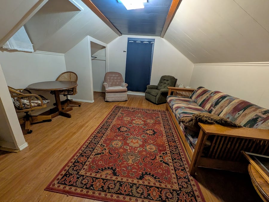 View from the door facing the window. Currently Set up like a Lounge area - can be used for relaxing and work or eating at the table - can switch out the couch for a bed if requested.