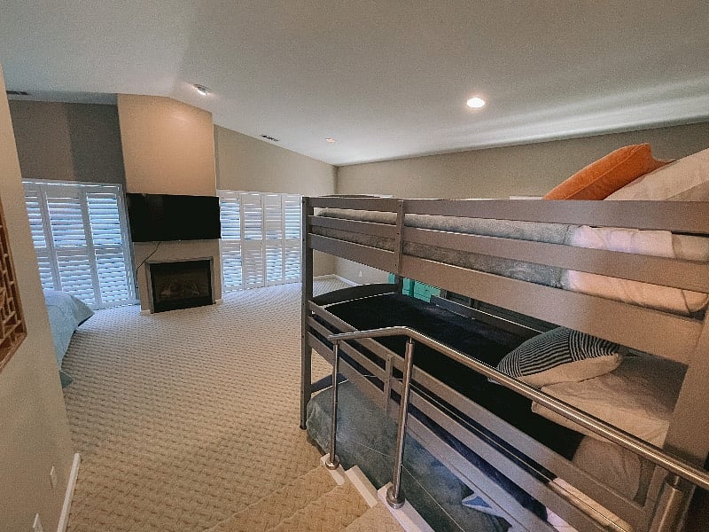 Upstairs bedroom with King Bed and Smart TV and Fireplace and 2 sets of triple high bunk beds. 