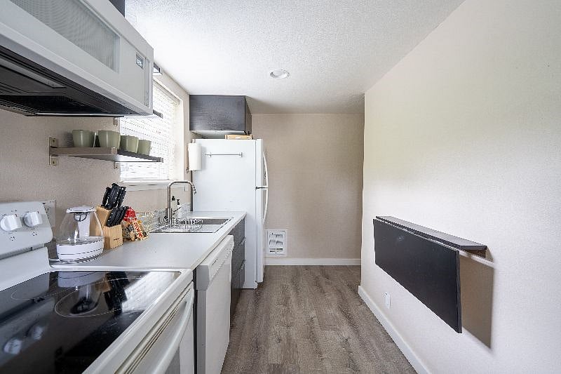 Kitchen with full sized refrigerator, oven, glasstop electric stove and over stove microwave oven. Water kettle, coffee maker and keurig machine in unit