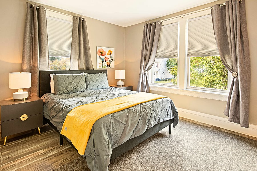 The second bedroom features a comfortable queen bed, blackout curtains, and treetop views. 