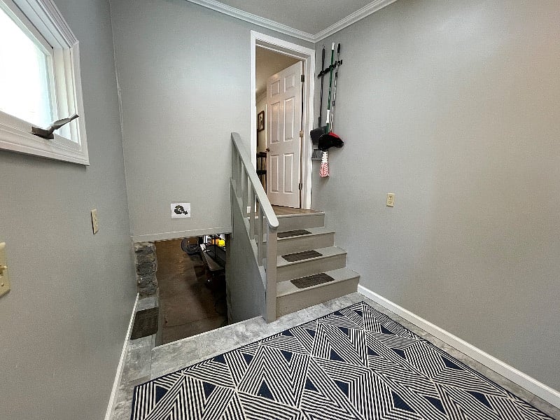 multi-purpose room showing half flight of stairs up to kitchen and down to basement and laundry area