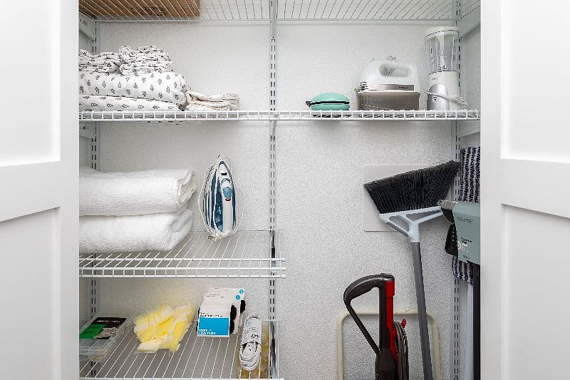 Linen closet stocked with extra towels, sheets, extra small appliances and cleaning supplies.