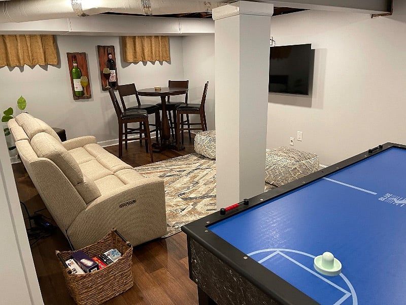 Partially furnished basement that can be used as an entertainment room. Game box next to the couch.