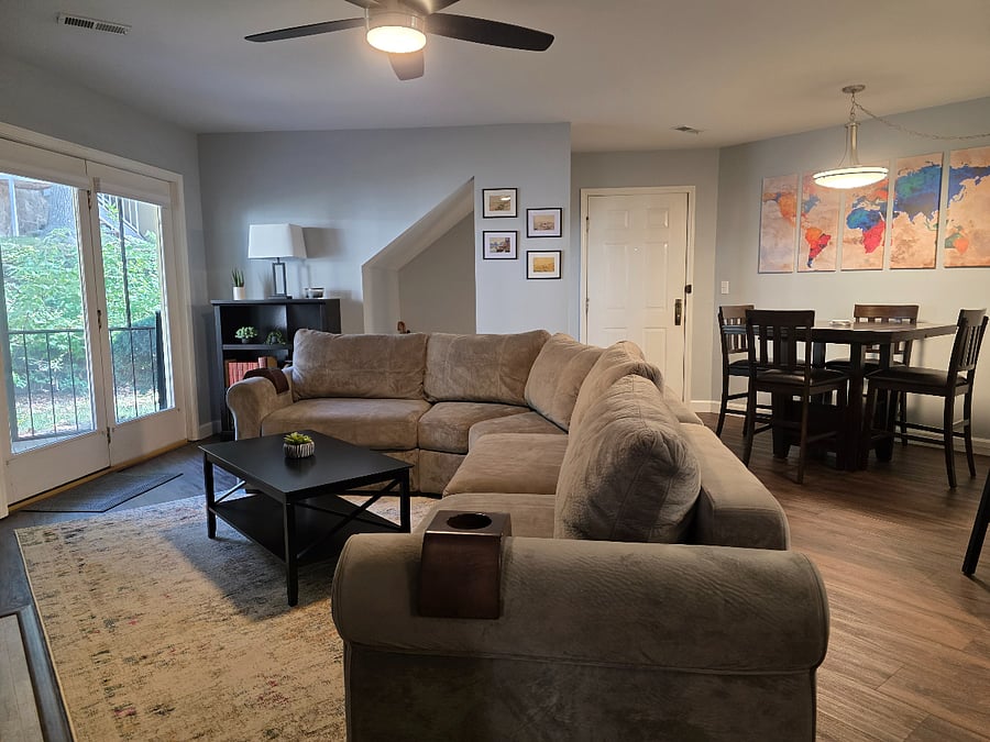 Living room has a large angled LoveSac couch, fireplace, and small television.
