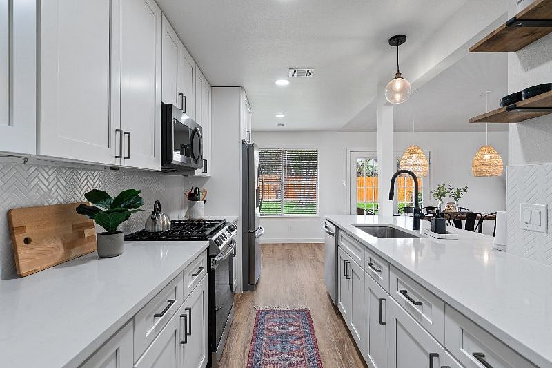 A bright galley kitchen with plenty of natural light, fully stocked with everything needed for everyday cooking.