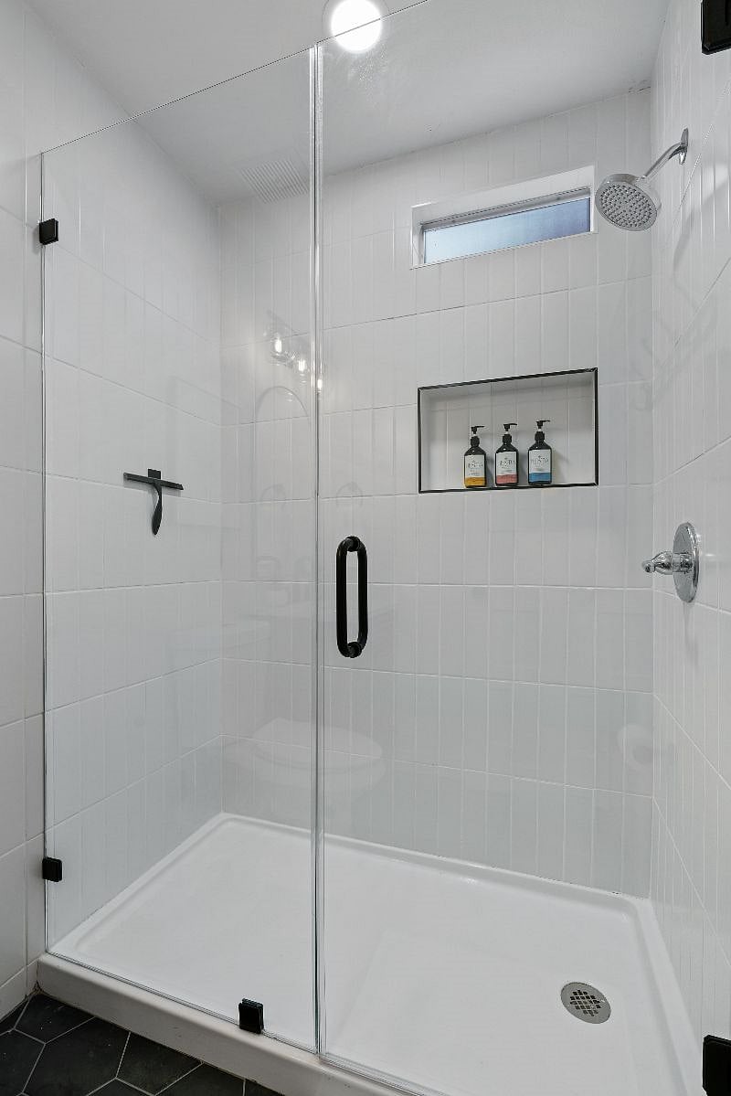 The primary bathroom features a walk-in shower with frameless glass door, along with a starter supply of shampoo, conditioner, and body wash for your convenience.