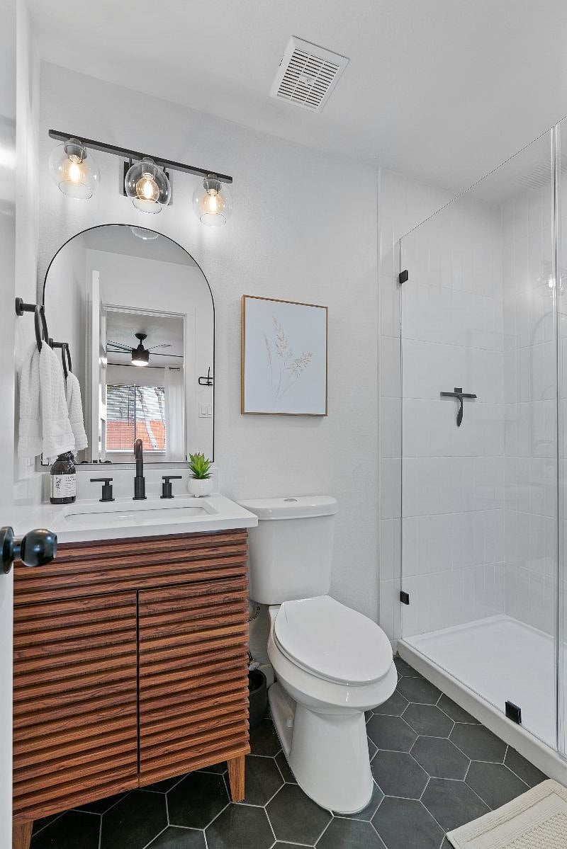 The primary bathroom features a walk-in shower with frameless glass door, along with a starter supply of shampoo, conditioner, and body wash for your convenience.