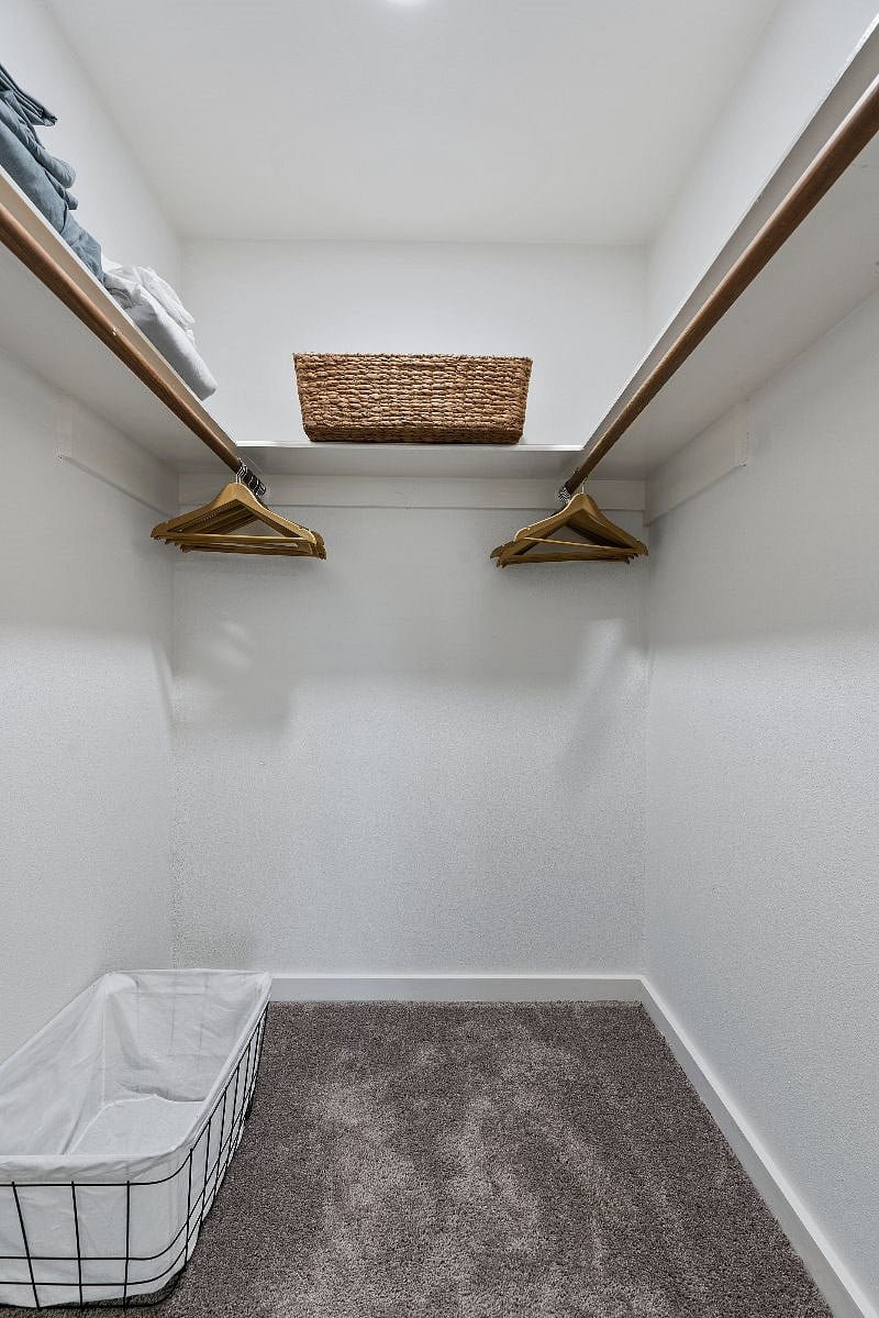Primary suite walk in closet with hangers and extra linen and towels