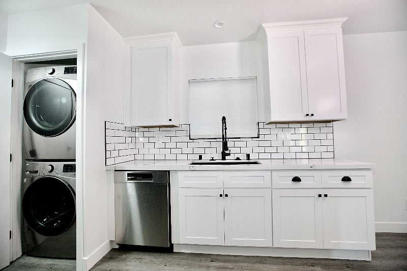 Modern kitchen with a dish washer machine, washer, dryer, refrigerator, stove and microwave.