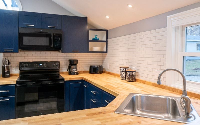 Blue kitchen with butcher block counter. Microwave, coffee maker