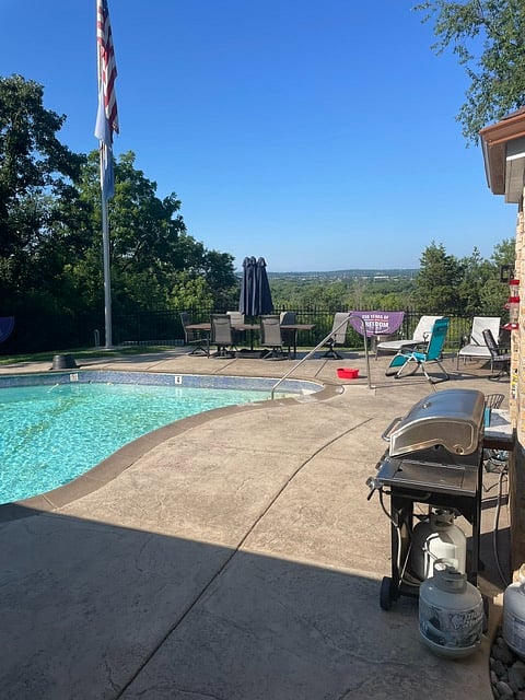 Large in ground pool with huge stamped concrete area with 2 large tables and 2 umbrellas.