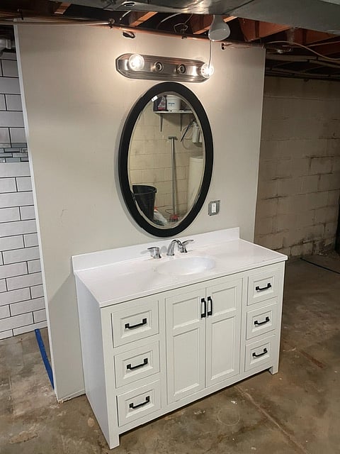 Vanity and mirror off of living area in unfinished lower level area.