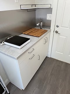 new granite kitchenette. full size chrome sink. cutting board sits atop sink. new auto shut off induction burner, when not in use (as pictured) easily stores above microwave atop the refrigerator.