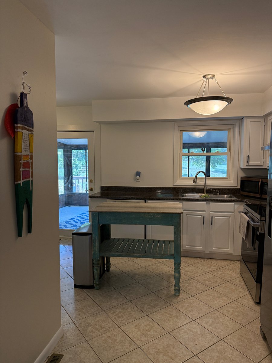 Kitchen area with all new cabinets, stove and fridge. Island and small kitchen table