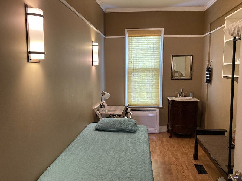 Small bedroom with twin bed, study area and sink with filtered water