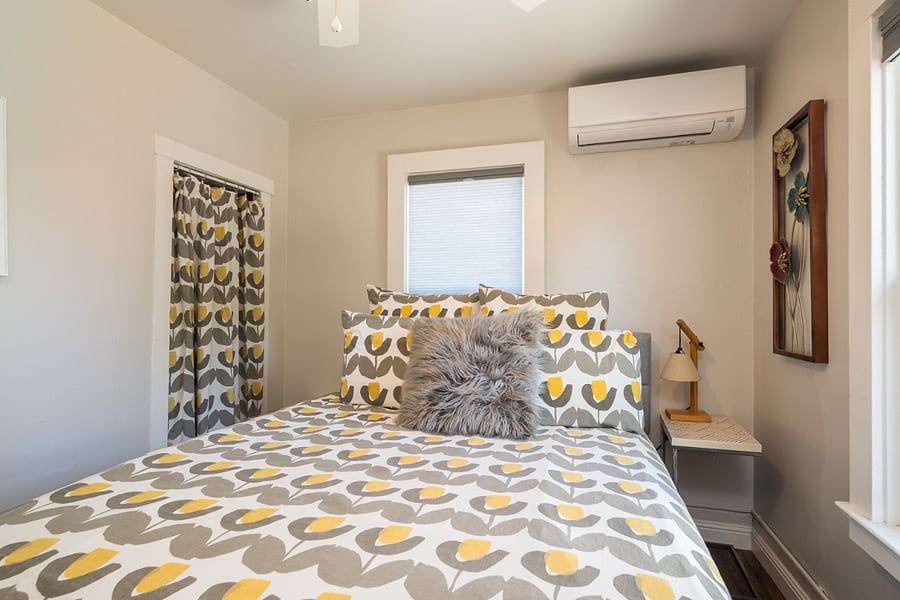 Downstairs bedroom with queen bed and wall-mounted mini-split for air conditioning or heat. Cute curtained closet with iron and ironing board.