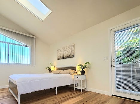 Main bedroom with fireplace, skylight, desk, private patio with ocean views