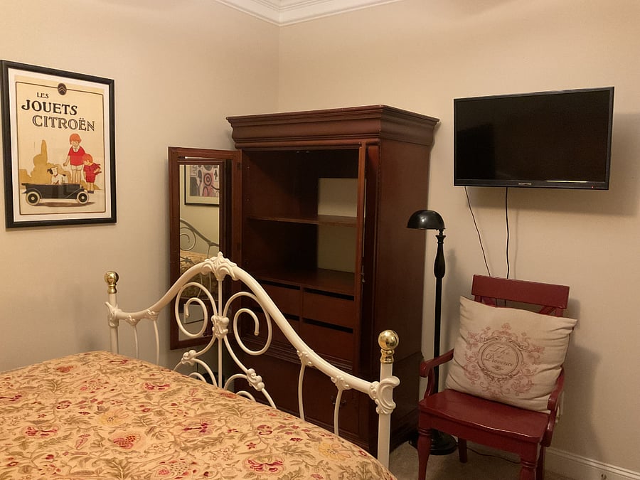 Spacious armoire with full-length mirrors. Wall-mounted 32 TV. Chair and floor lamp for additional lighting.
