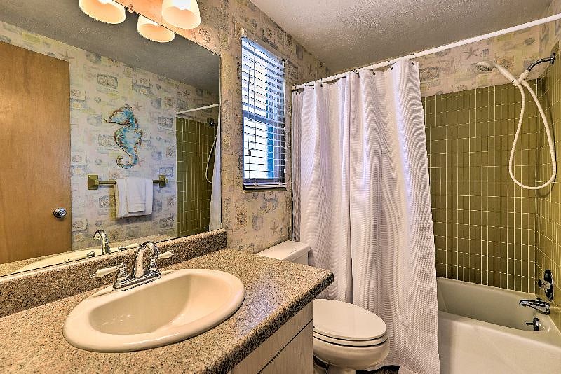 Guest bathroom has tub/shower combo and equipped with hair dryer.