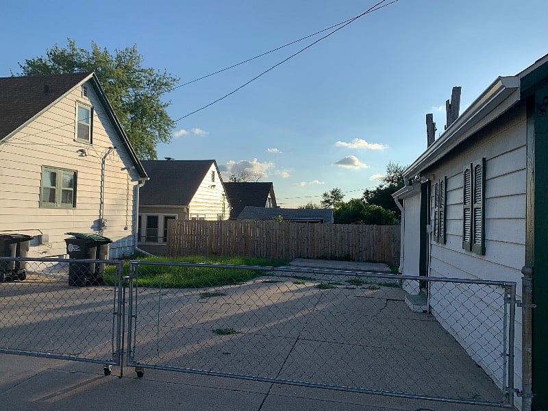 Driveway with enough room for 2 cars, behind a fence/gate, with side door to the left which enters to the kitchen