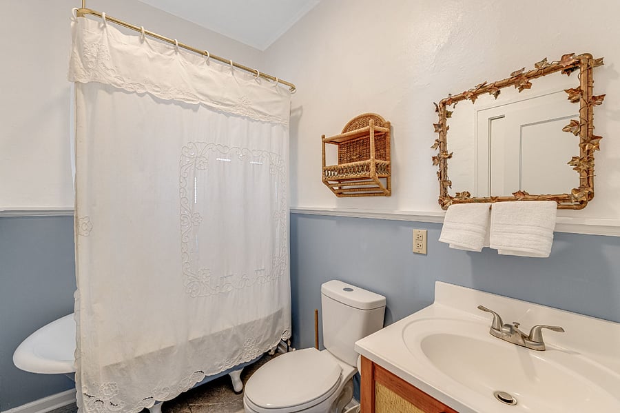 Bath room with clawfoot tub, hand made vanity and handmade leaf mirror.