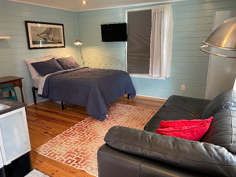Full sized bed, smart TV, and leather sofa.