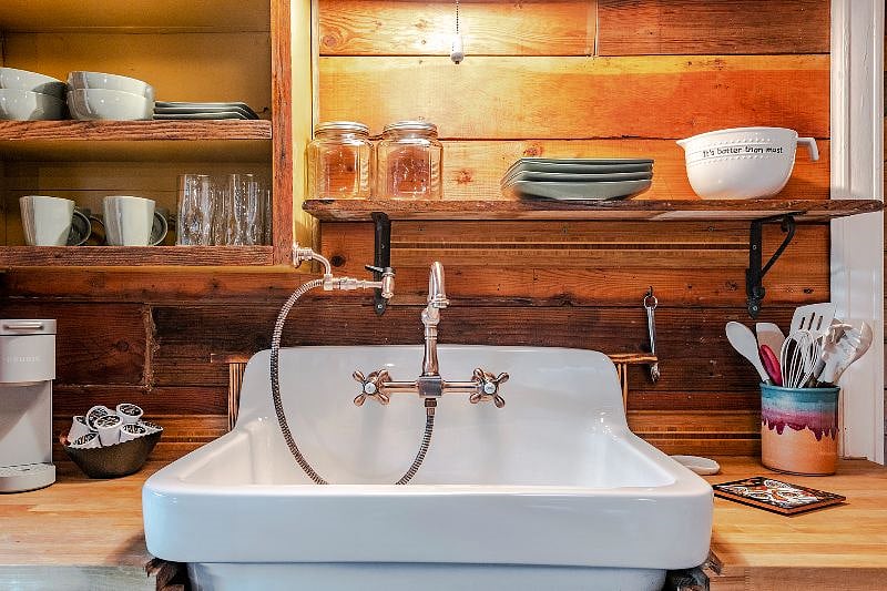 Enjoy using this beautiful farmhouse sink complete with a copper faucet. This sink sits on a cabinet constructed of salvaged wood from the main house.