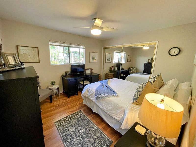 Bedroom with a queen size bed, desk, dresser and night stand with view of the patio and garden.