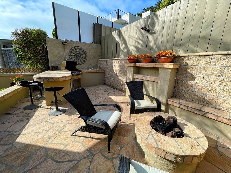 Outdoor kitchen with built in BBQ, sink, mini fridge and fire pit.